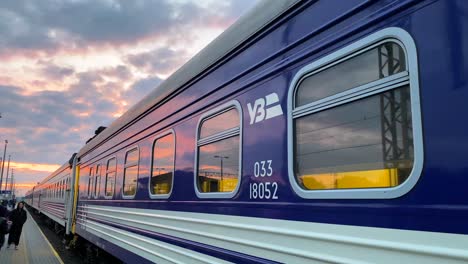 Ukrainian-Railways-Ukrzaliznycia-train-with-beautiful-pink-sunrise-sky-at-the-Chelm-train-station-in-Poland,-Ukrainian-refugees-waiting-to-board-early-morning-train-to-Kyiv-Ukraine,-4K-shot