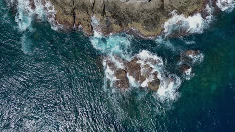 Drone-aerial-panning-view-of-waves-breaking-on-a-rocky-coastline