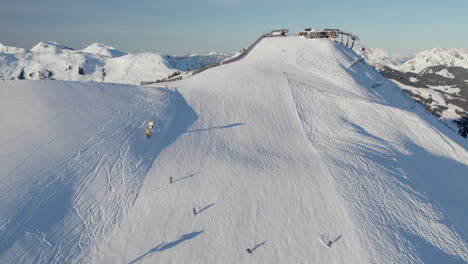 Skiers-Go-Down-The-Ski-Slope-On-Ski-Resort-In-Saalbach-Hinterglemm,-Austria---Drone-Shot