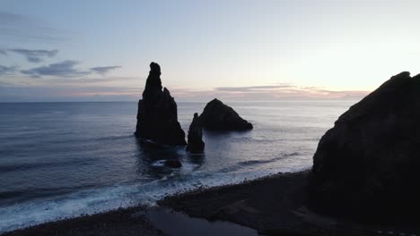 Luftdrohnenaufnahme-An-Der-Küste-Madeiras,-Wo-In-Der-Abenddämmerung-Eine-Ruhige-Meereslandschaft-Mit-Majestätischen-Felsformationen-Und-Ruhigen-Meereswellen-Sichtbar-Ist