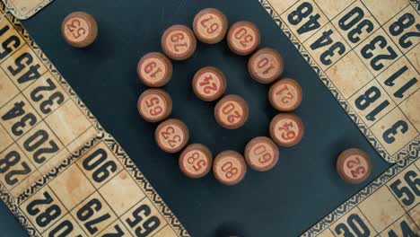 Creative-close-up-smooth-zoom-in-rotating-shot-from-above-of-a-Bingo-wooden-barrels-in-a-circle,-woody-figures,-old-numbers-background,-vintage-board-game,-professional-lighting,-slow-motion-120-fps