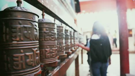 Woman-walks-past-prayer-wheels-and-spins-them-at-Swayambhunath-Temple,-Kathmandu,-Nepal