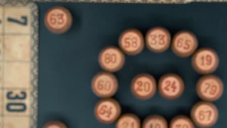 Cinematic-close-up-smooth-rotating-zoom-in-shot-from-above-of-a-Bingo-wooden-barrels-in-a-circle,-woody-figures,-old-numbers-background,-vintage-board-game,-professional-lighting,-slow-motion-4K