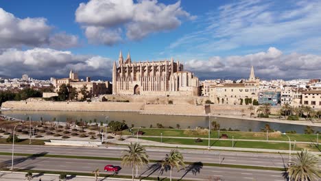 Ascending-drone-shot-showing-traffic-on-highway-and-famous-cathedral-of-Palma-de-Mallorca-in-Background