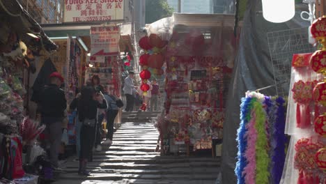 Profile-view-of-Central-Pottinger-Street-with-shops-and-people-buying-and-selling-during-sunny-day-in-Hong-Kong,-China