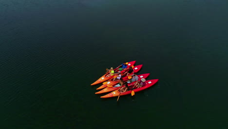 Menschen-Auf-4-Kajaks-Mitten-Im-See-Mit-Grünem,-Klarem-Wasser,-Paddelwassersport
