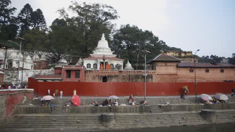 Rightward-pan-of-Pashupatinath-Temple,-with-a-cremation-ceremony-taking-place-in-the-temple,-Kathmandu,-Nepal