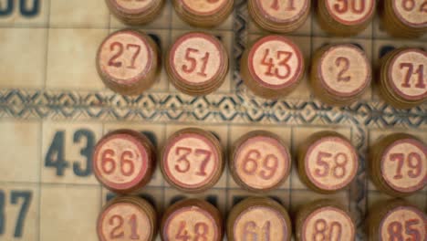 Cinematic-close-up-smooth-zoom-out,-shot-from-above-of-a-Bingo-wooden-barrels,-woody-figures,-old-numbers-background,-vintage-board-game,-lucky-number,-professional-lighting,-slow-motion-120-fps