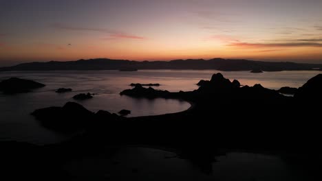 Drone-aerial-view-panning-over-landscapes-during-sunset-showing-silhouette-island-landscapes