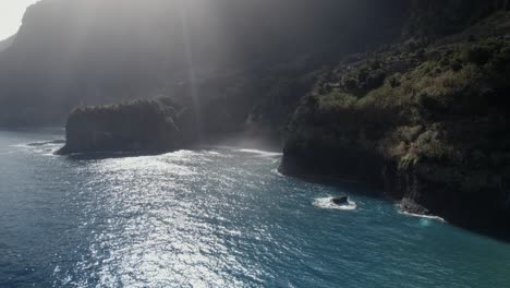 Luftdrohne-über-Dem-Meer-Geschossen,-Etwa-Ein-Lichtstrahl-Scheint-über-Dem-Ruhigen-Blauen-Meer-An-Grünen-Klippen-Auf-Madeira