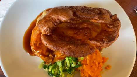 Traditional-British-Sunday-roast,-chicken-with-yorkshire-pudding,-gravy-and-vegetables,-classic-English-food,-lunch-dish-in-England,-top-view,-4K-shot