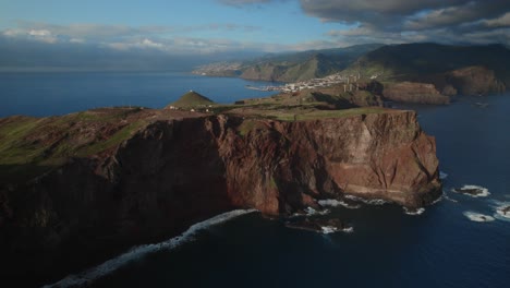 Drone-flying-over-the-sea-by-the-coast-at-Ponta-Do-Rosto,-Madeira-while-scenery-landscape-visible-in-the-background-with-waves-and-mountains