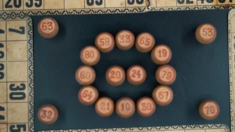 Cinematic-close-up-smooth-zoom-out,-shot-from-above-of-a-Bingo-wooden-barrels-in-a-circle,-woody-figures,-old-numbers-background,-vintage-board-game,-professional-lighting,-slow-motion-120-fps