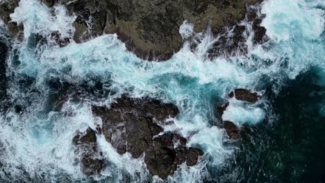 Drone-aerial-view-showing-waves-crashing-on-rocky-coastline