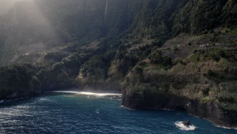 Drone-Aéreo-Disparado-Sobre-El-Mar-Sobre-Un-Rayo-De-Luz-Brilla-Sobre-El-Tranquilo-Océano-Azul-Junto-A-Acantilados-Verdes-En-Madeira