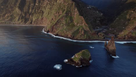Drohne-Fliegt-über-Das-Meer-Nahe-Der-Küste,-Während-Im-Hintergrund-Schroffe-Klippen-Und-Wellen-Sichtbar-Sind