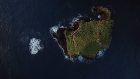 Aerial-top-shot-of-Isolated-island-surrounded-by-blue-sea-from-above-and-huge-waves