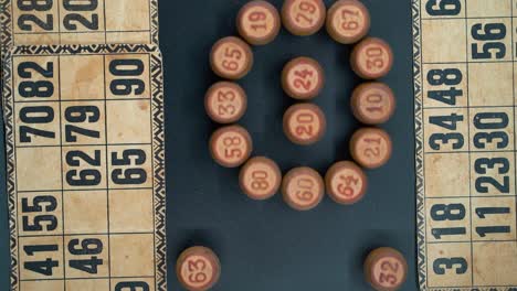 Creative-close-up-smooth-zoom-out-rotating-shot-from-above-of-a-Bingo-wooden-barrels-in-a-circle,-woody-figures,-old-numbers-background,-vintage-board-game,-professional-lighting,-slow-motion-120-fps
