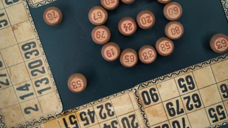 A-close-up-smooth-zoom-in-rotating-shot-from-above-of-a-Bingo-wooden-barrels-in-a-circle,-woody-figures,-old-numbers-background,-vintage-board-game,-professional-lighting,-slow-motion-120-fps