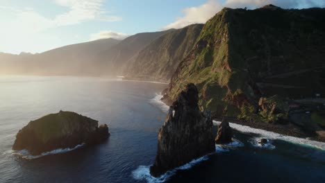 Aerial-view-with-drone-of-rugged-cliffs-and-isolated-rocks-in-the-ocean-during-golden-hour