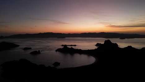Drone-aerial-moving-forward-over-islands-during-sunset-showing-silhouette-landscapes