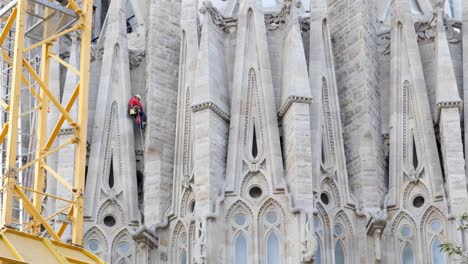 Die-Aufnahme-Von-Unten-Zeigt-Einen-Arbeiter-Am-Seil,-Der-Die-Fassade-Der-Sagrada-Família-In-Barcelona-Repariert