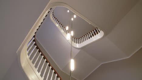 Una-Escalera-En-Un-Edificio-Histórico-Minimalista-Escandinavo-En-Copenhague-Con-Lámparas-De-Diseño-Desde-El-Techo