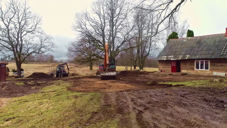 A-crane-and-a-tractor-are-busy-moving-the-sand-in-the-garden-of-a-farm