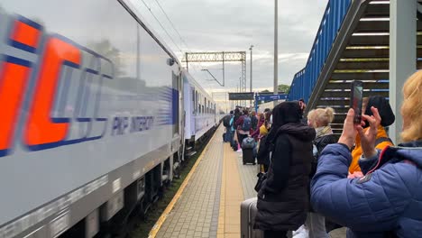Train-arriving-at-the-Chelm-train-station-in-Poland,-Ukrainian-refugees-waiting-to-board-the-Chelm-to-Warsaw-train,-people-fleeing-and-escaping-war,-4K-shot