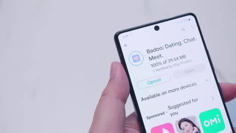 Nahaufnahme-Eines-Mobilen-Smartphones,-Während-Eine-Person-Die-Dating-Anwendung-Badoo-Herunterlädt-Und-Installiert