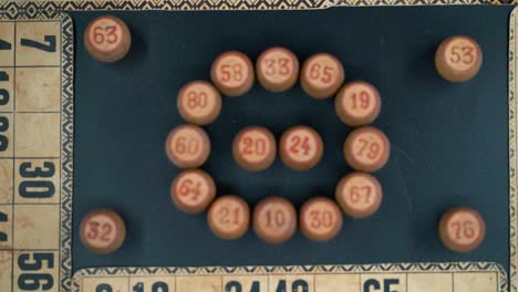 Cinematic-close-up-smooth-zoom-out,-shot-from-above-of-a-Bingo-wooden-barrels-in-a-circle,-woody-figures,-old-numbers-background,-vintage-board-game,-professional-lighting,-slow-motion-120-fps