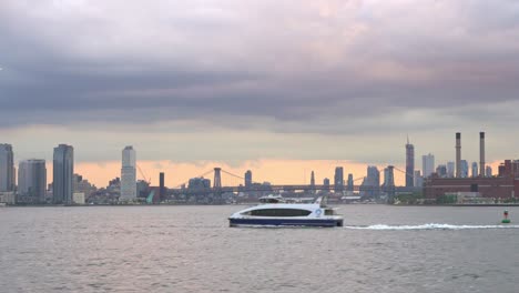 NYC-Ferry-Transport-Cruising-The-East-River-At-Sunset,-Urban-Skyline-Waterway