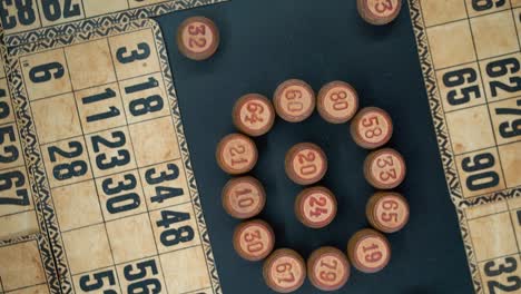 Cinematic-close-up-smooth-zoom-out-rotating-shot-from-above-of-a-Bingo-wooden-barrels-in-a-circle,-woody-figures,-old-numbers-background,-vintage-board-game,-professional-lighting,-slow-motion-120-fps