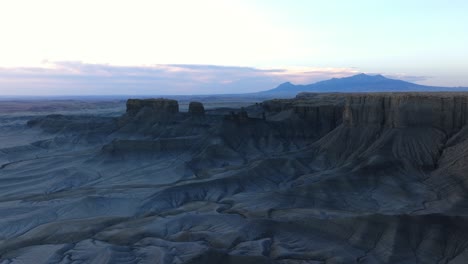 Filmische-Luftlandschaft-Von-Factory-Butte,-Utah-Bei-Sonnenuntergang,-Mann-Steht-Auf-Felsen