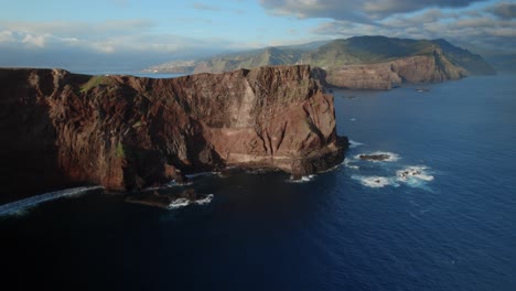 Drone-flying-over-the-ocean-an-sees-a-panoramic-view-of-towering-sea-cliffs-against-a-calm-ocean