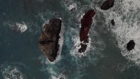 Aerial-top-shot-with-a-drone-at-Ponta-Do-Rosto-over-the-sea-about-rugged-cliffs-and-rocks,-waves