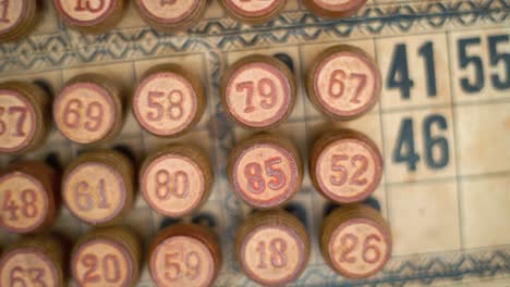 Cinematic-close-up-smooth-pan-left,-shot-from-above-of-a-Bingo-wooden-barrels,-woody-figures,-old-numbers-background,-vintage-board-game,-lucky-number,-professional-lighting,-slow-motion-120-fps
