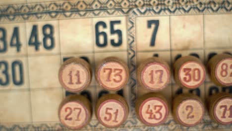 Cinematic-close-up-smooth-tilt-down,-shot-from-above-of-a-Bingo-wooden-barrels,-woody-figures,-old-numbers-background,-vintage-board-game,-lucky-number,-professional-lighting,-slow-motion-120-fps
