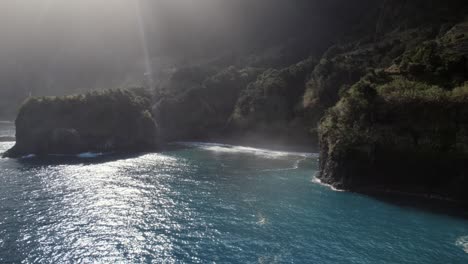 Aerial-drone-shot-over-the-sea-about-ray-of-light-shines-over-tranquil-blue-ocean-by-green-cliffs-at-Madeira