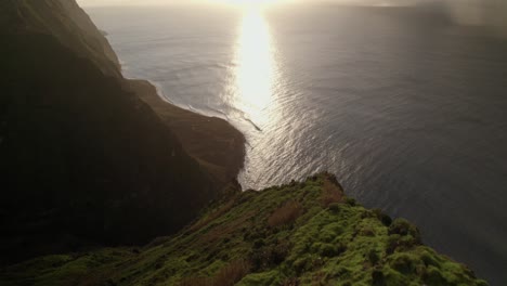 Luftdrohnenaufnahme-Einer-Malerischen-Küstenklippe-Bei-Sonnenuntergang-Mit-Glitzerndem-Ozean