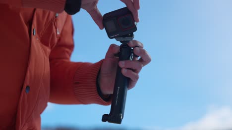 Person-in-orange-jacket-holds-Insta360-action-camera-and-detaches-it-from-handle-with-magnetic-clip
