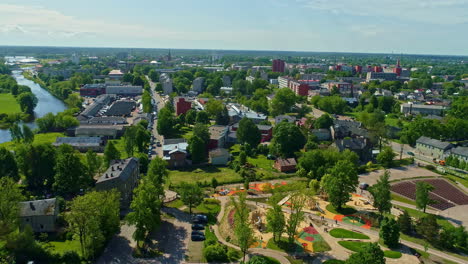 Luftaufnahme-Eines-Farbenfrohen-Parks-Und-Spielplatzes-In-Der-Nähe-Des-Flusses-In-Jelgava,-Lettland