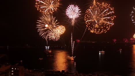 Tilt-up-aerial-view-of-a-group-of-boats-on-the-shore-of-Valparaiso,-New-Year's-Eve-fireworks-display,-Chilean-coastline