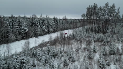 Car-Parked-On-Snowy-Road-Through-Coniferous-Forest-On-Gloomy-Winter-Day