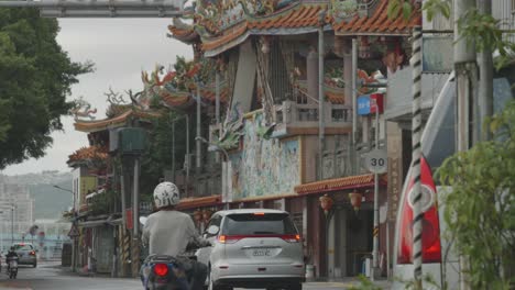 Pan-to-Guandu-temple-street-as-cars-and-motorbikes-drive-past