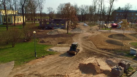 Aerial-footage-of-a-mini-digger-driving-over-a-construction-site