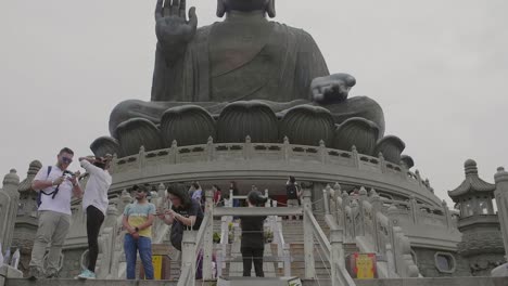 Tian-Tan-Buddha-statue-during-an-overcast-day-with-many-tourists-below-taking-pictures-and-sightseeing---Super-Slow-Motion