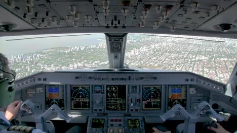 Pilots-in-cockpit-flying-over-urban-landscape,-view-of-city-from-above-from-inside-the-aircraft