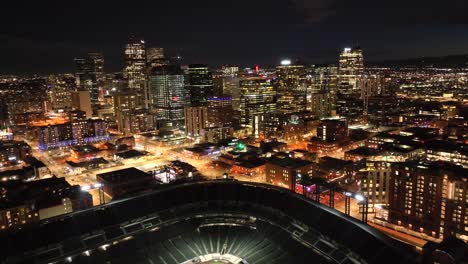 Aerial-Drone-nighttime-reverse-over-downtown-Denver-Skyline-and-Coors-field-baseball-stadium