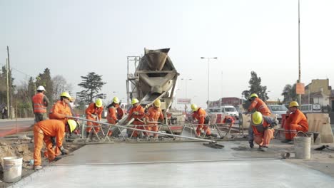 Construction-workers-in-high-visibility-clothing-leveling-fresh-concrete-on-road